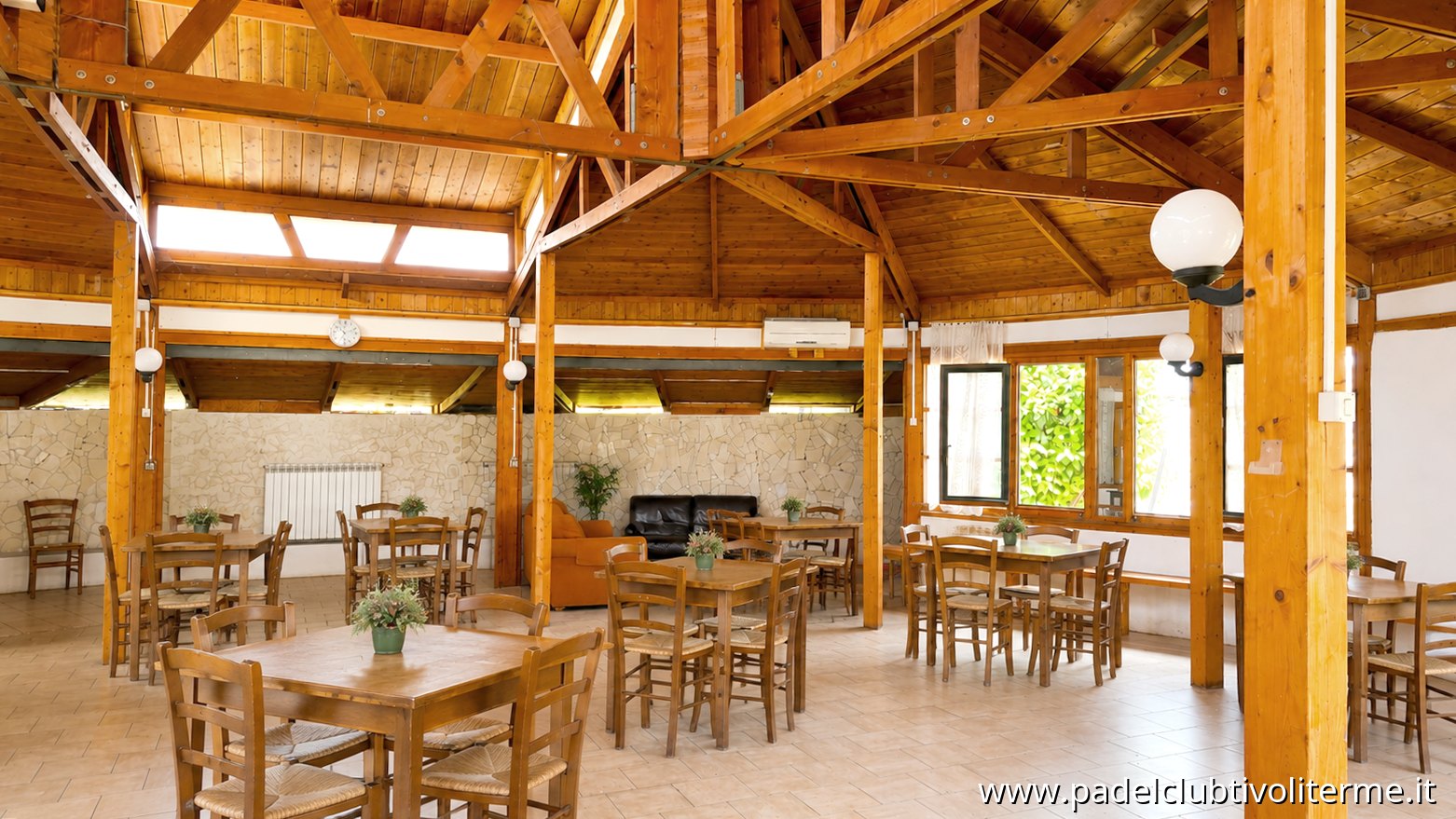 Sala interna in legno con tavoli e travi a vista